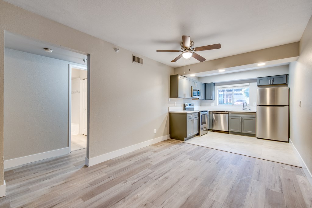 an empty living room and kitchen with a ceiling fan