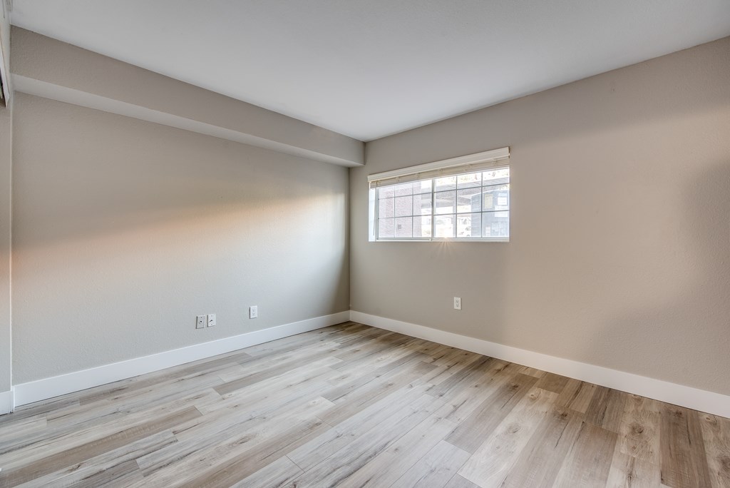 an empty room with wood floors and a window