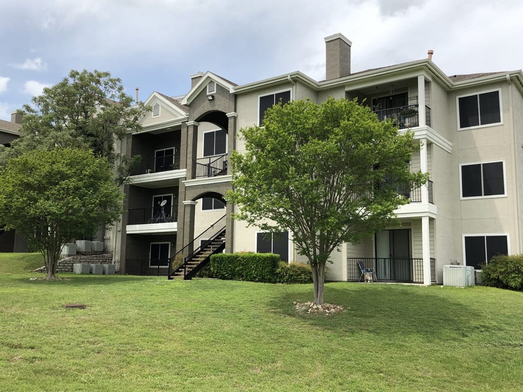 an apartment building with grass and trees in front of it