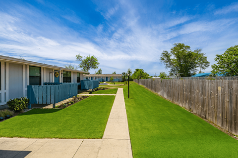 the yard of a home with green grass and a sidewalk