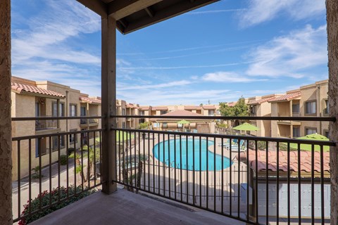 A view from a balcony overlooking a pool and apartment buildings.