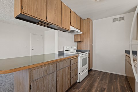 A kitchen with wooden cabinets and a white stove top oven.