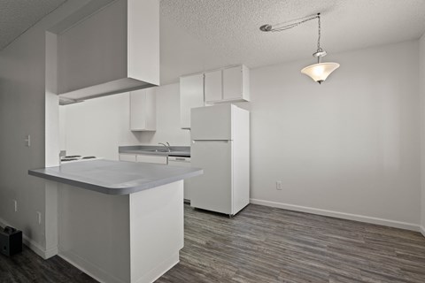 A kitchen with white cabinets and a wooden floor.