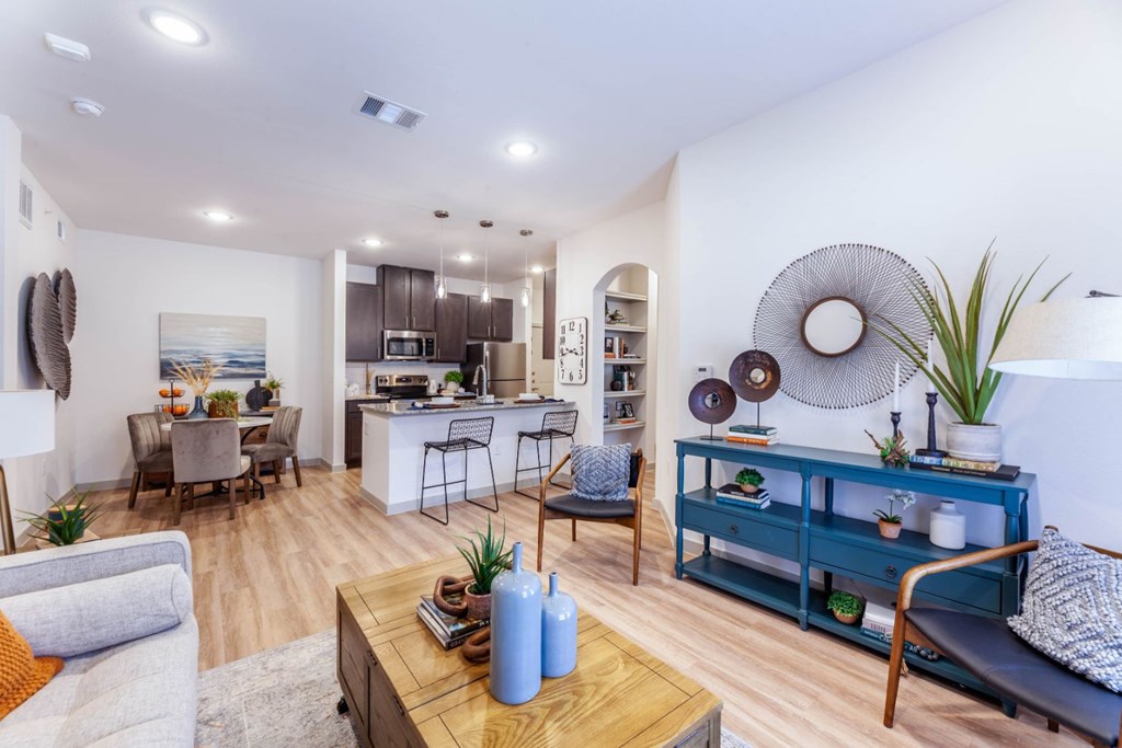 A modern living room with a kitchen in the background.