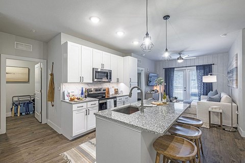 A modern kitchen with white cabinets and a granite countertop.