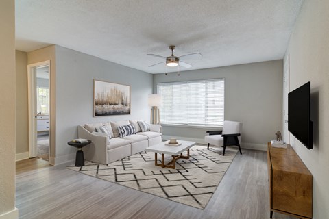 A living room with a couch, a chair, a coffee table, and a painting on the wall.