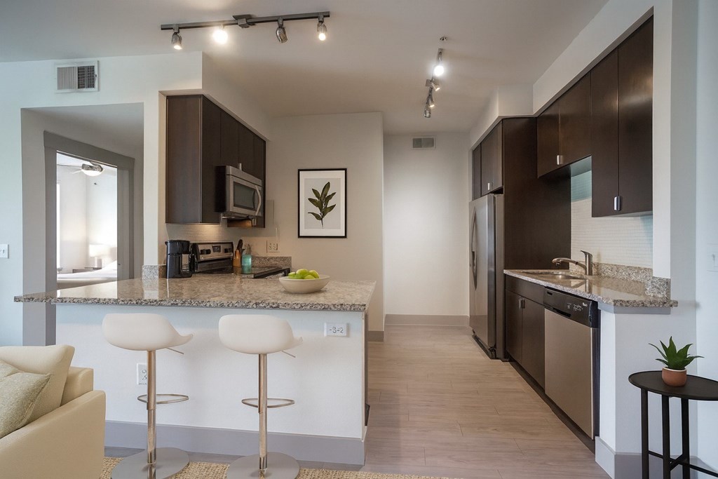 A kitchen with a white counter top and a fridge.