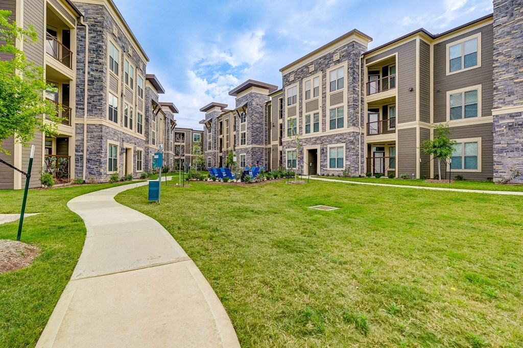 Courtyard with grassy area and a walkway in front of an apartment building