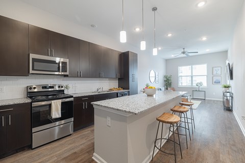 A modern kitchen with dark brown cabinets and stainless steel appliances.