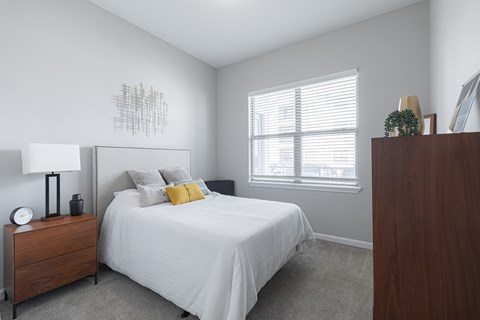 A bedroom with a bed, nightstand, and a wall art.