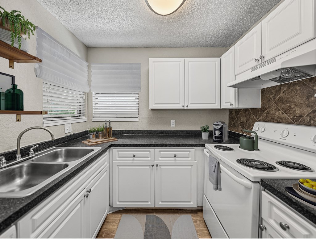 A kitchen with white cabinets and a black countertop.