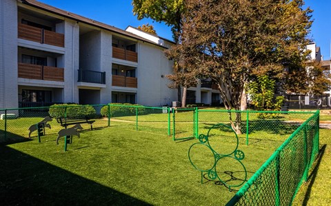 A green fence surrounds a small grassy area with a playground.
