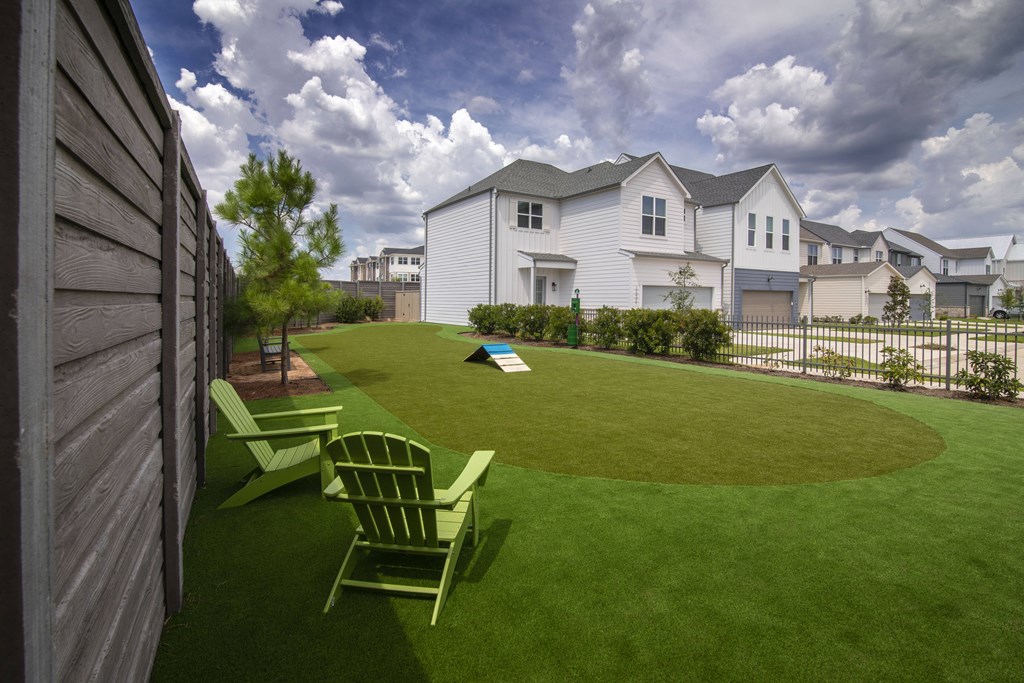 A white house with a green lawn and a wooden fence.