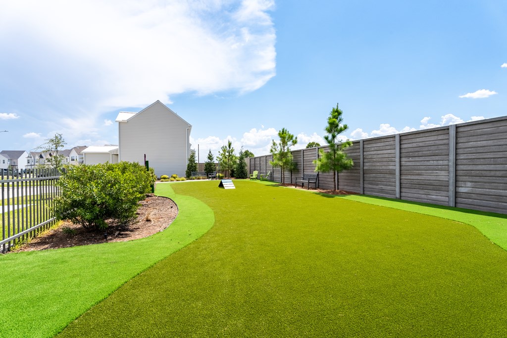A white house is surrounded by a green lawn and a fence.