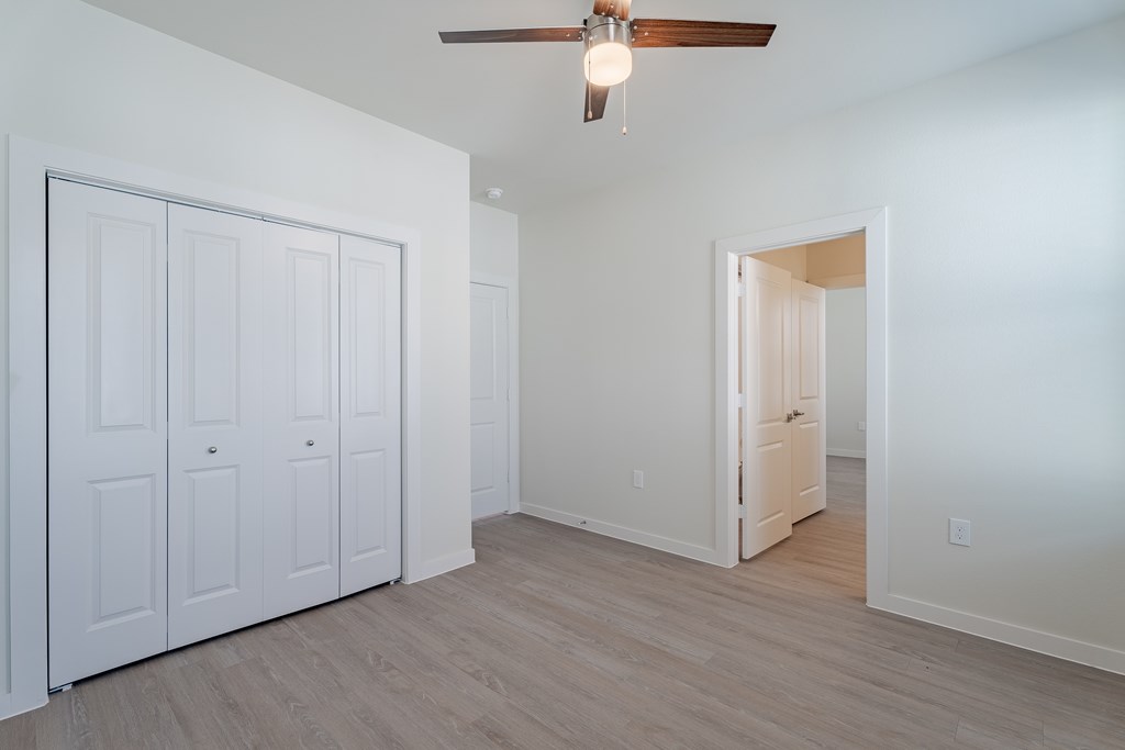 A room with a ceiling fan and white walls.