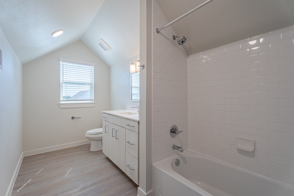 A white bathroom with a tub, toilet and sink.