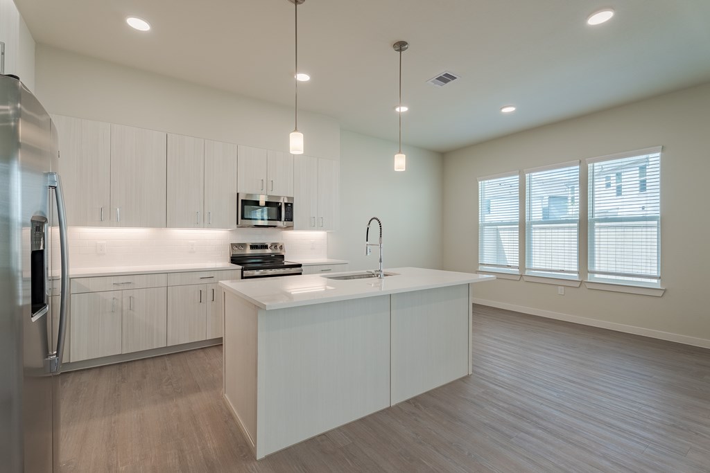 A modern kitchen with a refrigerator, microwave, and a sink.