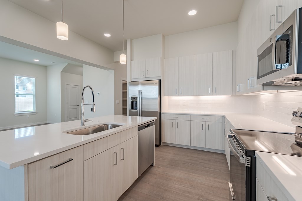 A modern kitchen with white cabinets and stainless steel appliances.