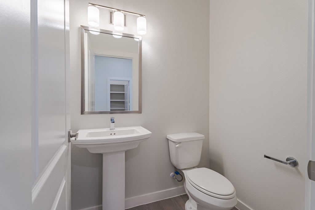 A white sink and toilet in a bathroom with a mirror above it.
