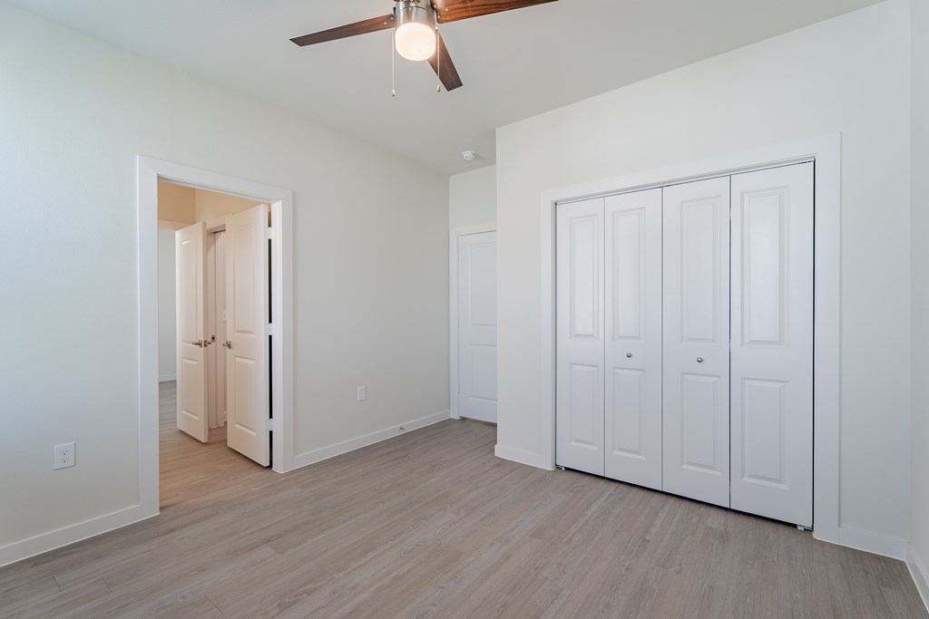 A room with a ceiling fan and three white doors.
