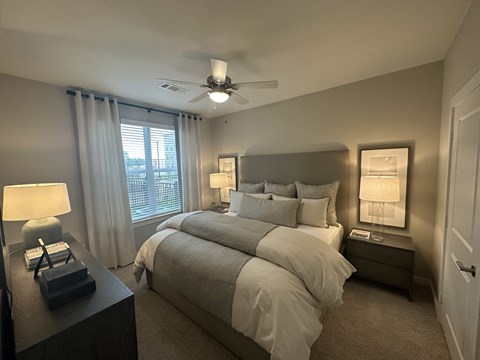 A bedroom with a large bed and a ceiling fan.