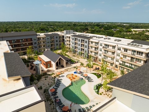 A view of a resort with a pool and a green lawn.