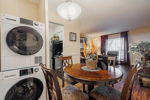 a kitchen with a washing machine and a dining room with a table and chairs
