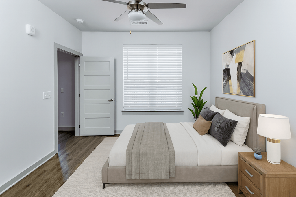 A bedroom with a bed, nightstand, and a ceiling fan.