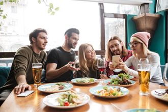 a group of people sitting around a table with food and drinks