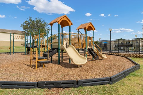 A playground with a yellow slide and two orange towers.