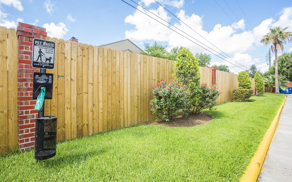 a backyard with a wooden fence and a sign in the grass