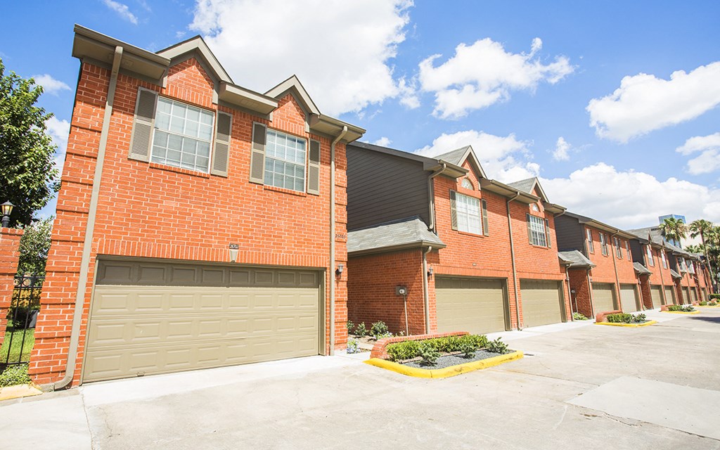 an empty parking lot in front of a brick building with garages