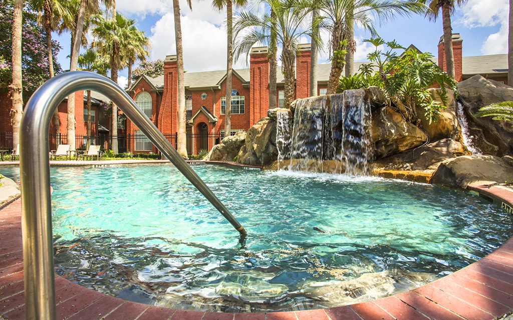a pool with a waterfall in front of a house
