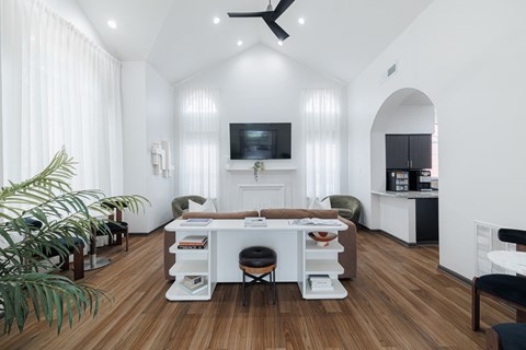 A modern living room with a white sofa, a white coffee table, and a television on the wall.