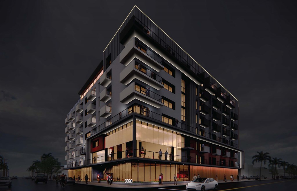 A modern building with a curved design and balconies is shown at night.