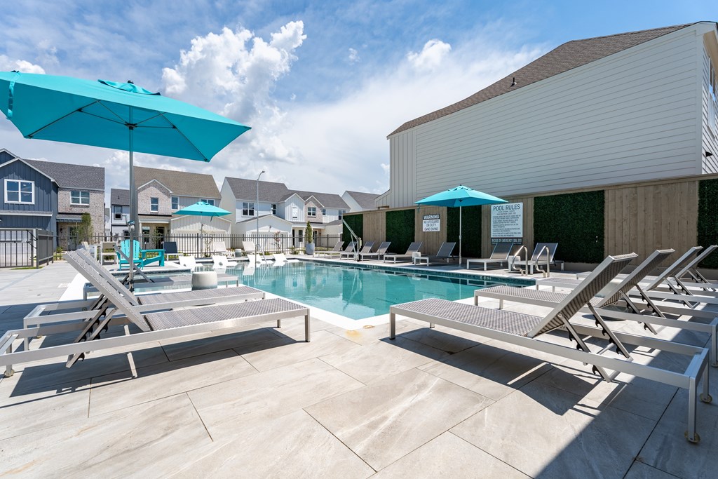 A pool area with sun loungers and umbrellas.