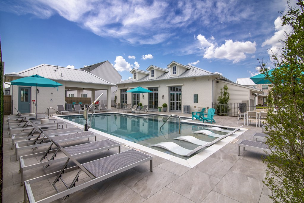 A pool with sun loungers and a building in the background.