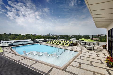 A large outdoor swimming pool with a wooden deck and lounge chairs.