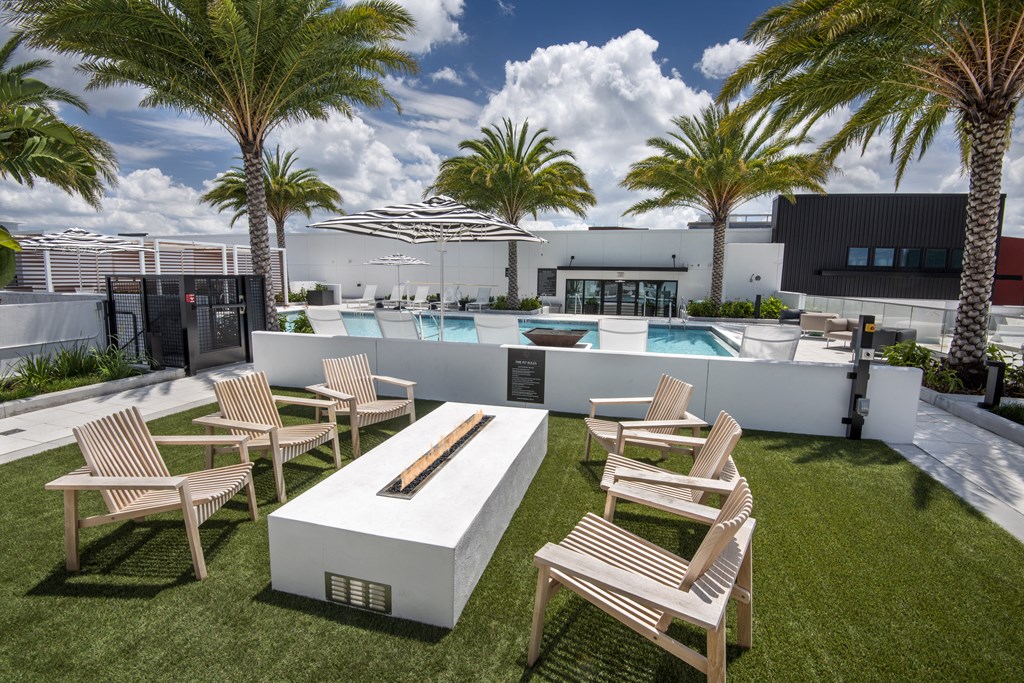 a patio with chairs and a fire pit and a pool