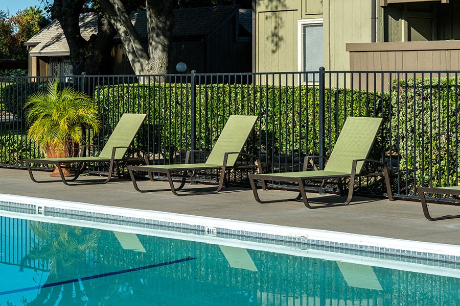 two lawn chairs sitting next to a swimming pool