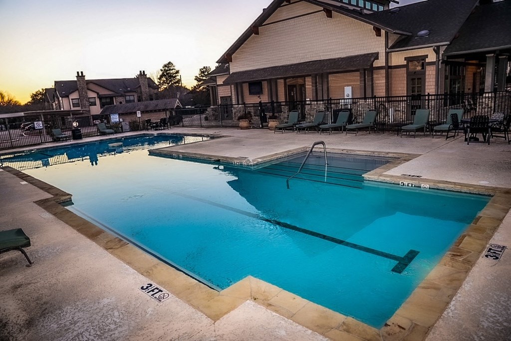 a swimming pool with chairs around it in front of a building