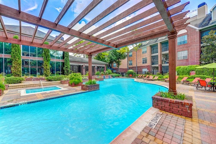 A large outdoor swimming pool with a wooden pergola over it.