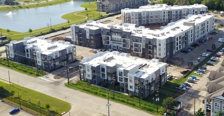 a block of apartment buildings with white roofs and a lake in the background
