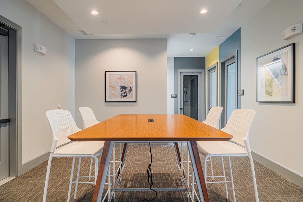 a meeting room with a long wooden table and white chairs