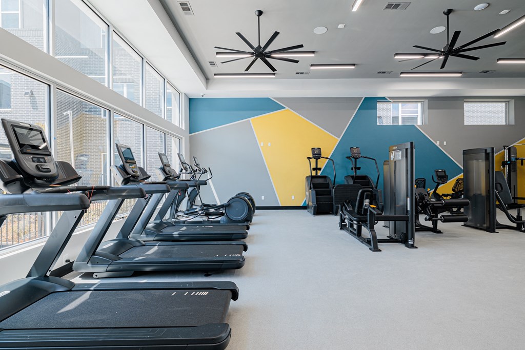 a spacious fitness center with cardio machines and windows