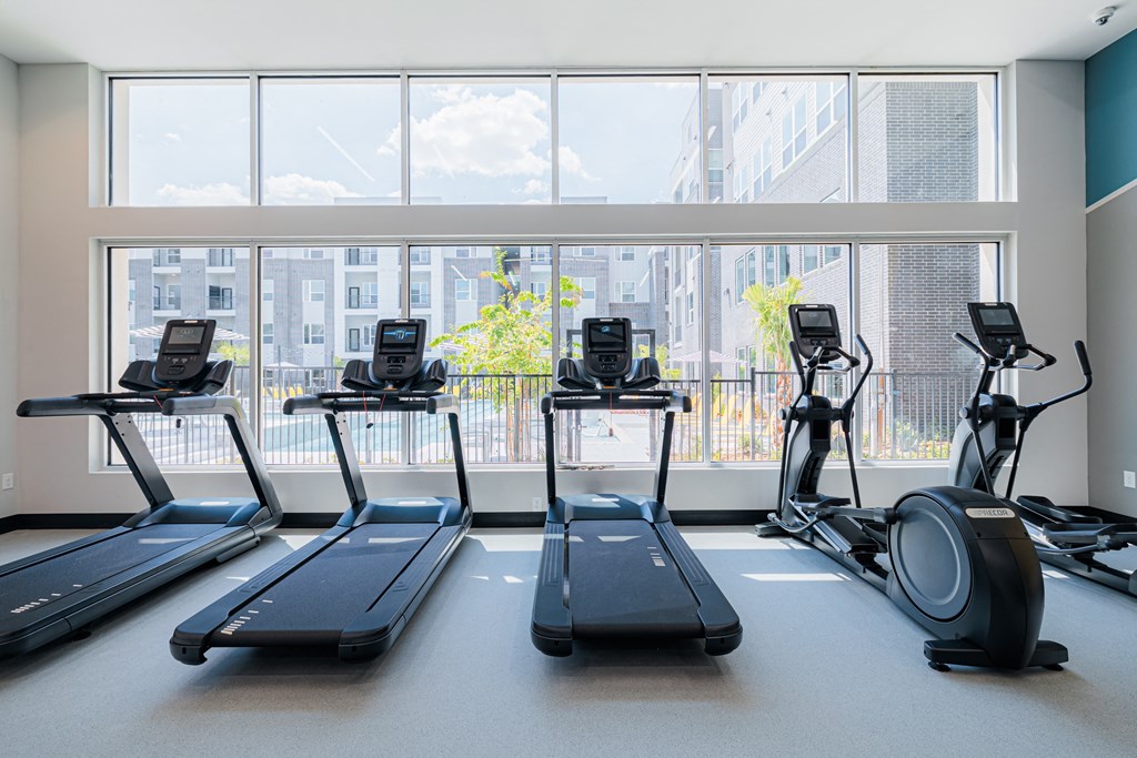 a gym with four treadmills and a large window