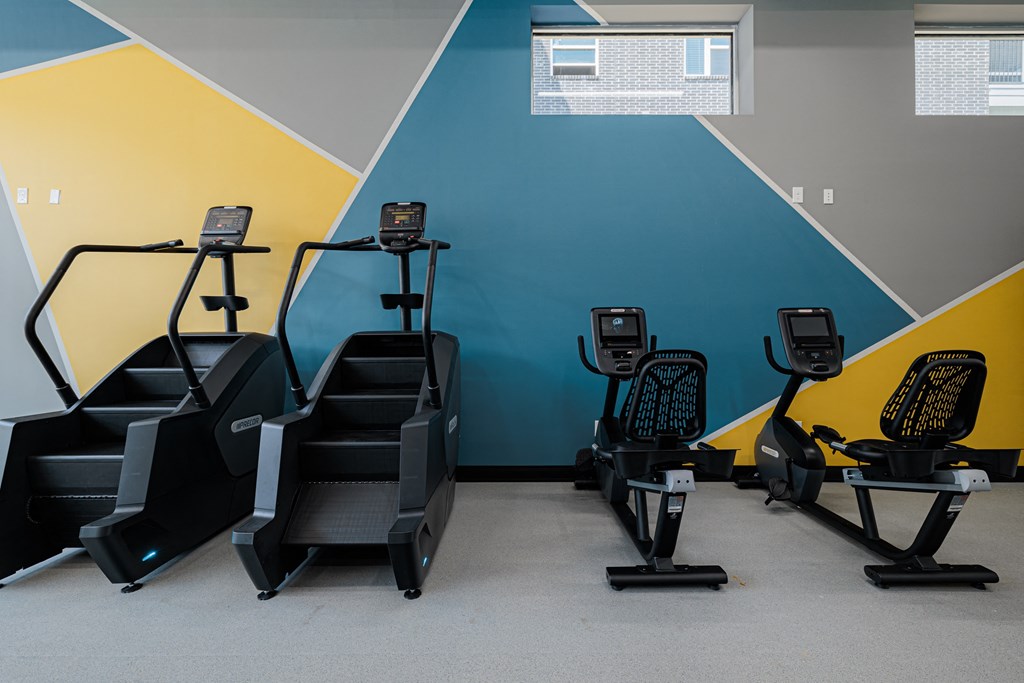 a row of exercise bikes in a gym with a blue and yellow wall