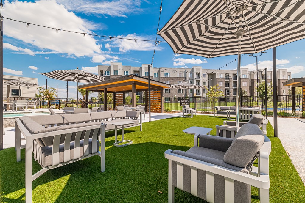 an outdoor lounge area with lounge chairs and umbrellas at the enclave at woodbridge apartments