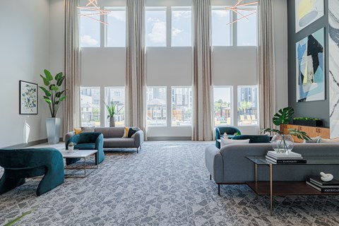 a living room with couches and chairs and large windows