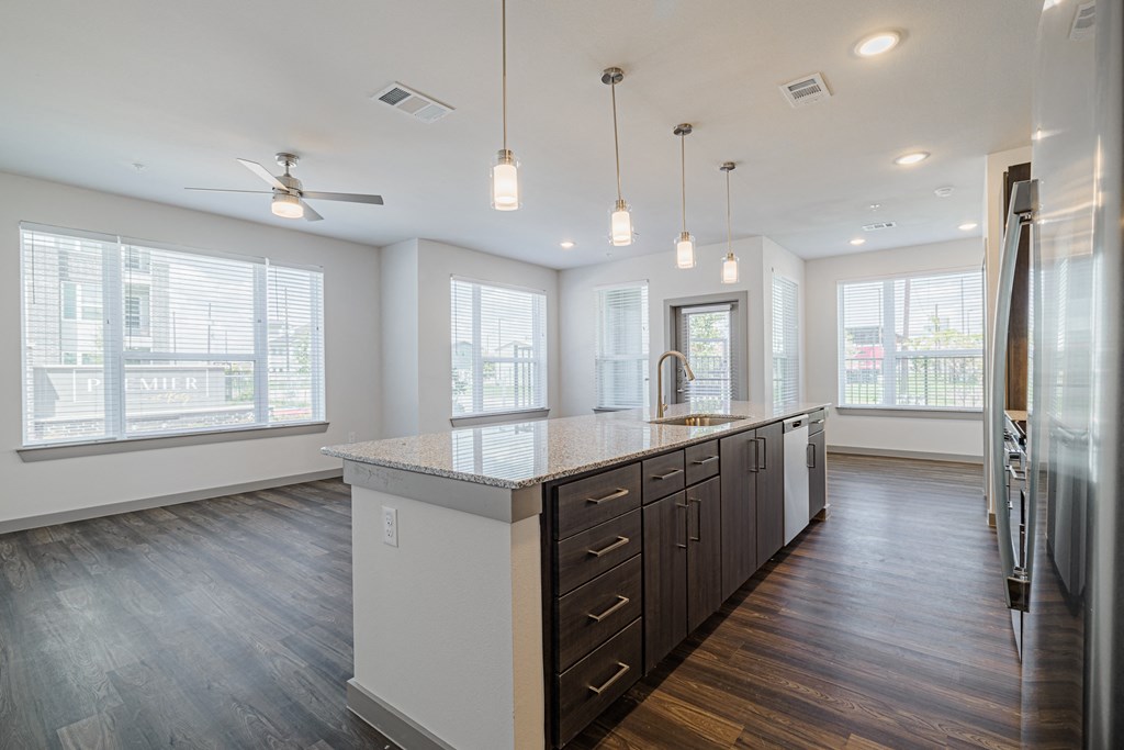 a kitchen with a large center island with a sink and a refrigerator